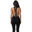Rear view of dark-haired model displaying open back cutout and branded vertical text strap on black dress with leggings