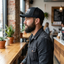 Seated man displaying curved brim and foam-to-mesh transition on black flexfit trucker hat