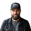 Man in black denim jacket wearing black trucker hat with white patch reading BECAUSE I'M A GIVER